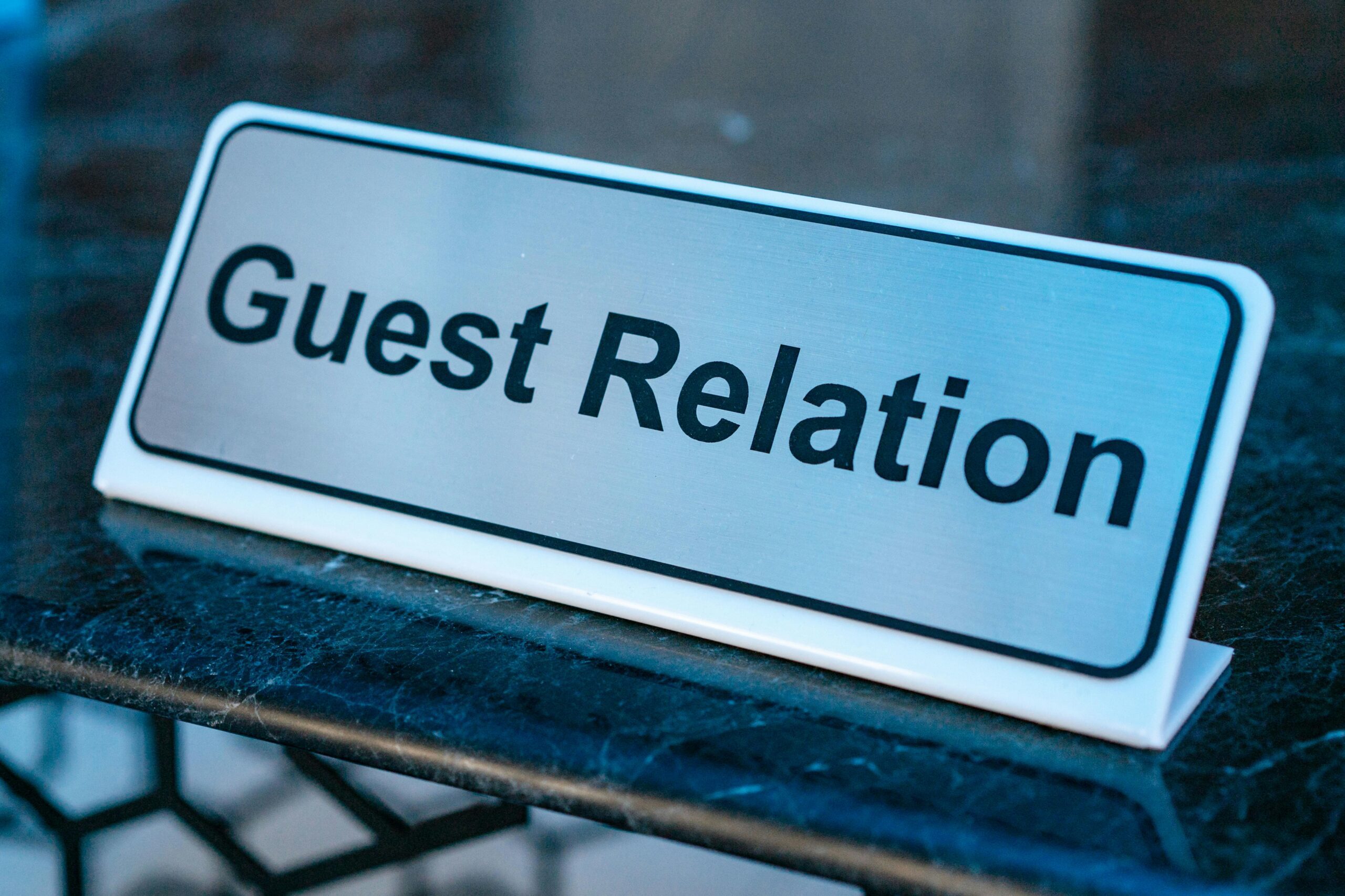 Close-up of a guest relation sign on a granite reception desk, ideal for hospitality services.