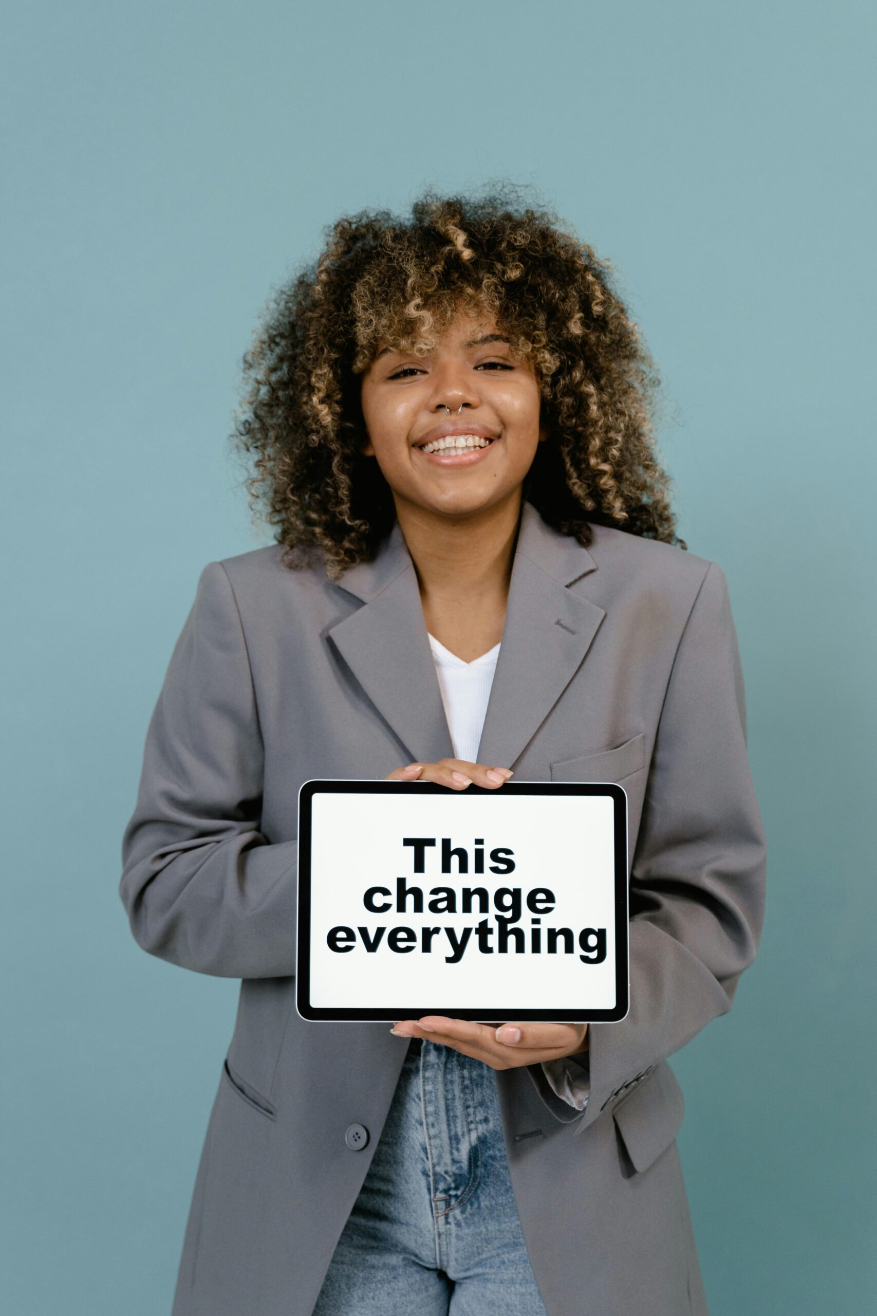 Young woman smiling while holding a sign that reads 'This change everything'.